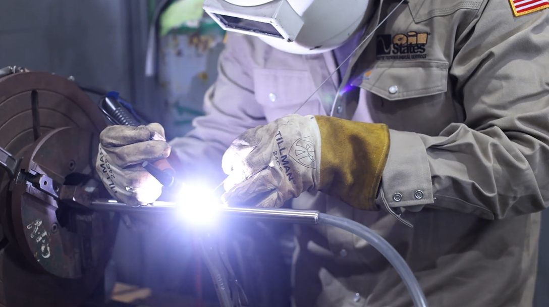 Close up view of welding with weld light in the center and the worker with proper safety gear on